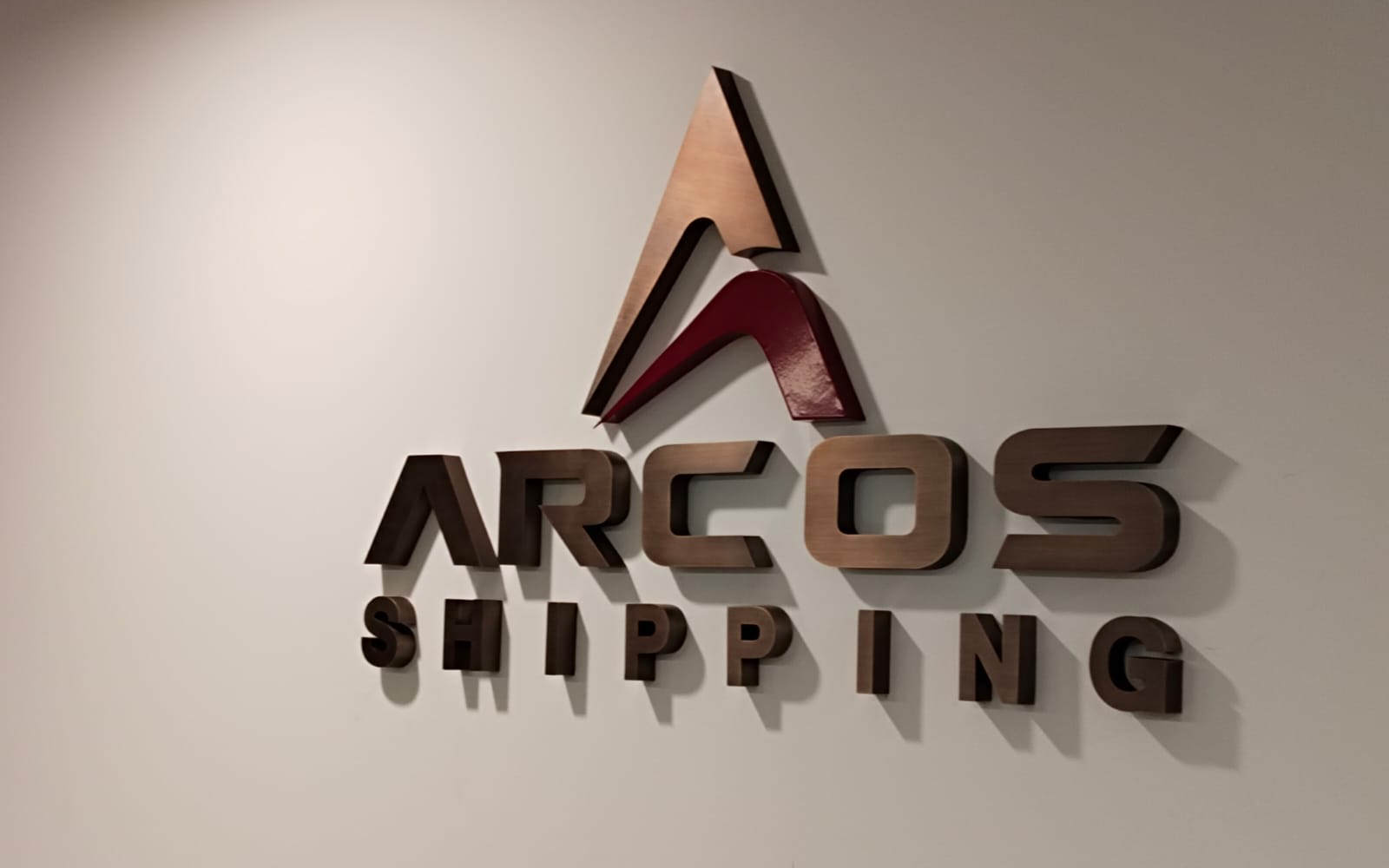 Raised Arcos Shipping logo and letters on a plain wall